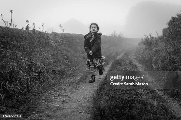 little girl running along a country lane on a misty day. she is dressed as a witch and riding a broomstick - cleaning equipment stock pictures, royalty-free photos & images