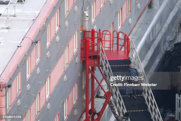 Person carrying luggage walks onto the Bibby Stockholm immigration vessel at Portland Port, on October 30, 2023 in Portland, England. According to a...