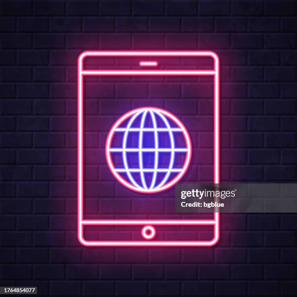 tablet pc with globe. glowing neon icon on brick wall background - touch screen wall stock illustrations