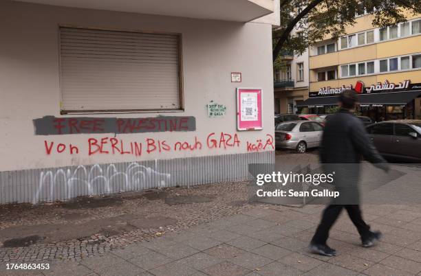 Man walks past graffiti that reads: "Free Palestine" and "From Berlin to Gaza" on Sonnenallee in the city's Neukoelln district on October 30, 2023 in...