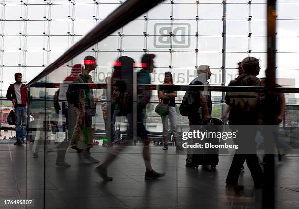 Travelers pass in front of the logo of Deutsche Bahn AG as it sits on display on the glass facade of Berlin Central Station, also known as...