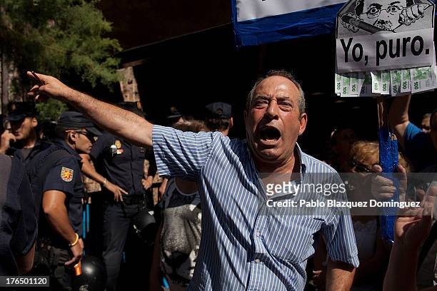 Protester affected by preference shares shout while another holds a placard depicting Spanish Prime Minister Mariano Rajoy after PP General Secretary...