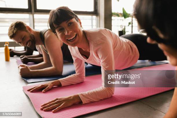 happy businesswoman practicing plank position with colleagues on mats at office - büro sport stock pictures, royalty-free photos & images