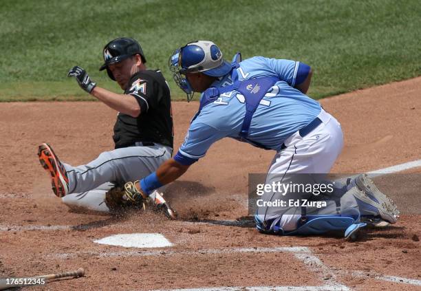 Greg Dobbs of the Miami Marlins is tagged out by Salvador Perez of the Kansas City Royals as he tries to score on a Jake Marisnick single in the...