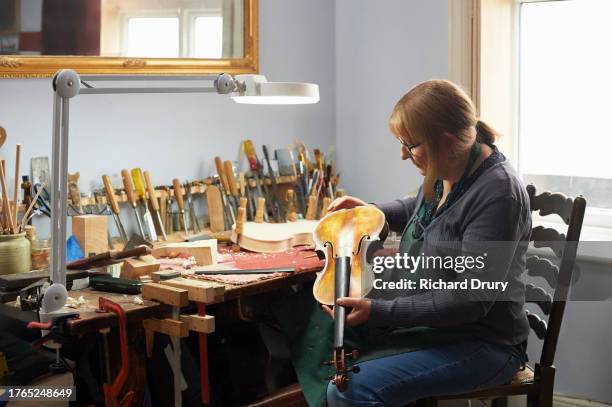 violin maker examining an instrument - violin family stock pictures, royalty-free photos & images