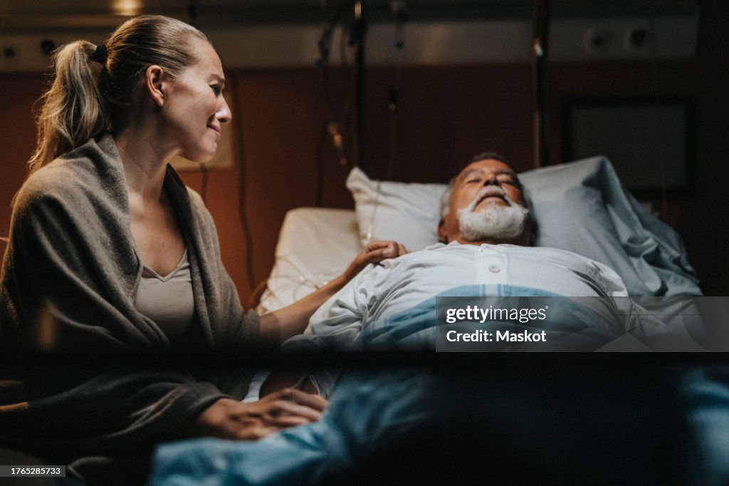 Depressed mature daughter crying near father in hospital ward