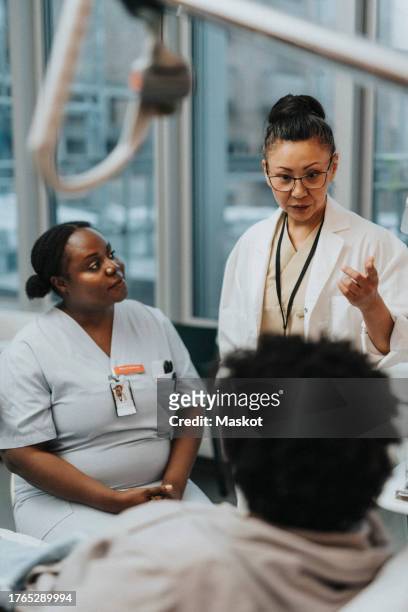female doctor advising patient while doing visit in hospital ward - icu ward stock pictures, royalty-free photos & images
