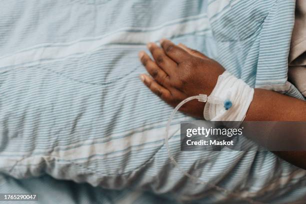 hand of patient with iv drip on bed in hospital - iv drip womans hand stock pictures, royalty-free photos & images