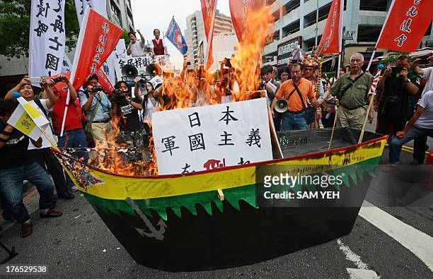 Protesters burn a model made of paper to represent Japan's recently unveiled warship, the new 248-metre helicopter carrier DDH183 Izumo, during a...