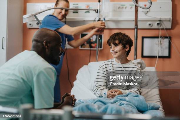 male medical staff talking with boy sitting on bed in hospital ward - children dreams 2011 open day of kids hospice stockfoto's en -beelden