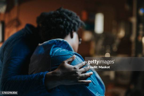 woman with arm around depressed female friend at healthcare center - consolare foto e immagini stock