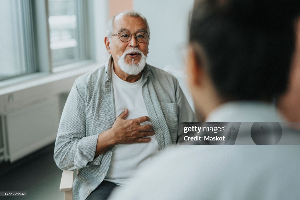 Elderly male patient receiving good news while sitting with doctor during consultation at hospital