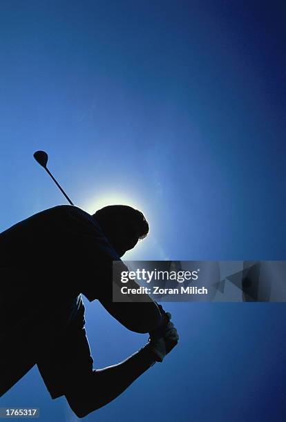 Golfer silhouetted against sky, low angle view