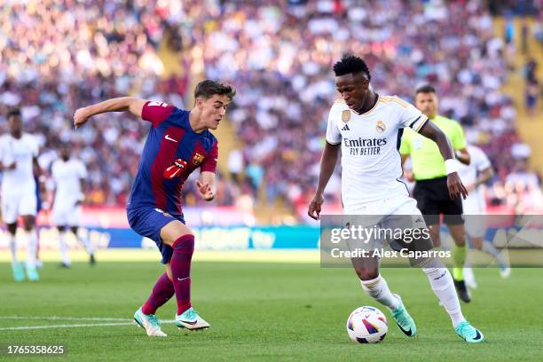 Vinicius Junior of Real Madrid CF runs with the ball whilst under pressure from Pablo Paez 'Gavi' of FC Barcelona during the LaLiga EA Sports match...