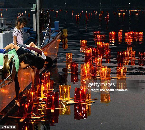 Children release candle-lit paper lanterns to the ocean from a fishing boat ahead of Obon festival on August 14, 2013 in Ishinomaki, Miyagi, Japan....