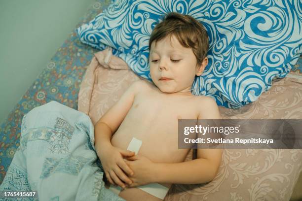 child holding his stomach after surgery while lying in hospital - hernia recovery stock pictures, royalty-free photos & images