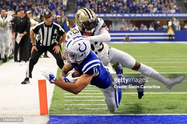 Michael Pittman Jr. #11 of the Indianapolis Colts dives into the end zone past Marshon Lattimore of the New Orleans Saints while scoring a receiving...