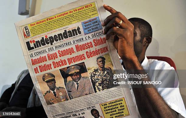 Man looks at the front pages of newspapers on August 15, 2013 in Bamako showing the leaders of the coup, Amadou Sanogo, Moussa Sinko Coulibaly and...