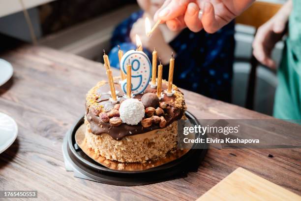 small chocolate bento cake and a hand lights a candle with the number 9 with a match - bento box stock pictures, royalty-free photos & images