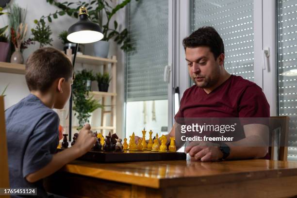 man playing chess with little brother - chess timer stock pictures, royalty-free photos & images