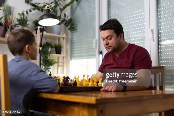 man playing chess with little brother - chess timer stock pictures, royalty-free photos & images