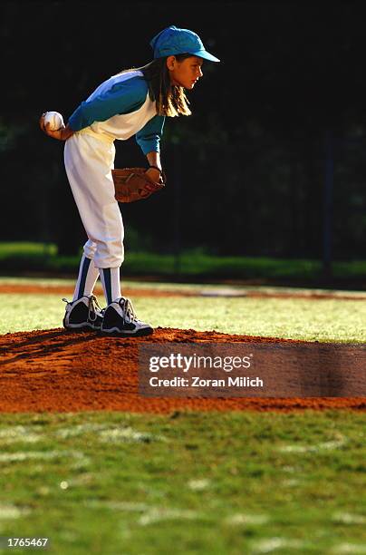 Girl playing baseball, standing on pitcher''s mound