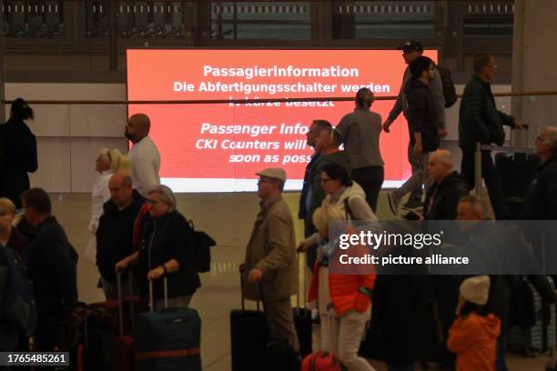 November 2023, Hamburg: Travelers are on the move in Terminal 1 at Hamburg Airport, a neon sign reads "The check-in counters will be manned shortly"....