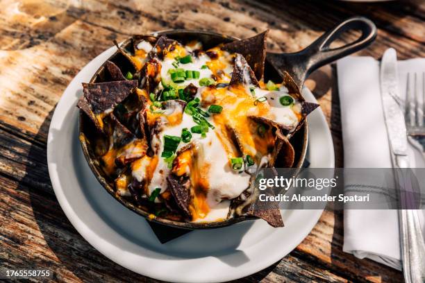 nachos with cheese and sour cream served in a skillet - nachos guacamole stock pictures, royalty-free photos & images