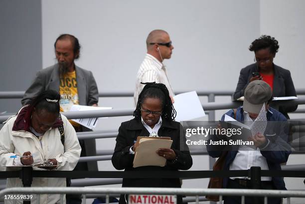 Job seekers fill out applications as they wait in line to enter a job fair at a new Target retail store on August 15, 2013 in San Francisco,...