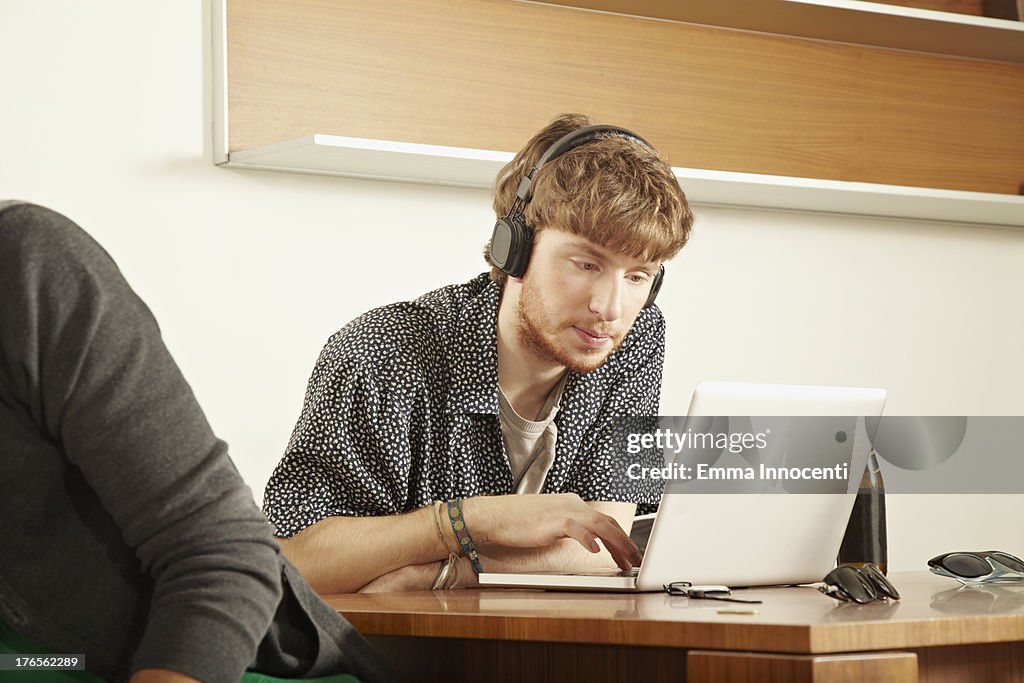 Young man indoor listening to  music with laptop