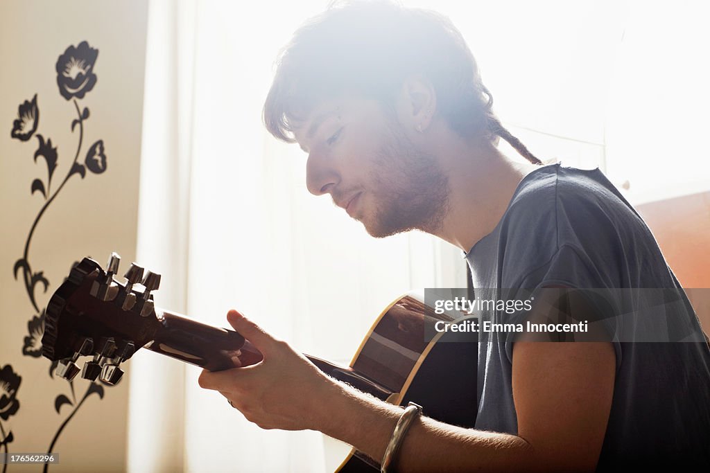 Young man playing guitar indoors