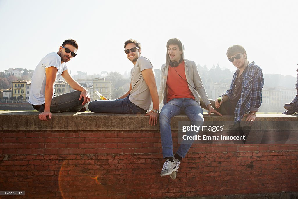Young men sitting outdoor on brick wall