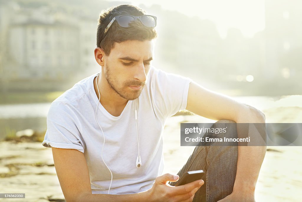 Young man looking at the mobile phone in the sun