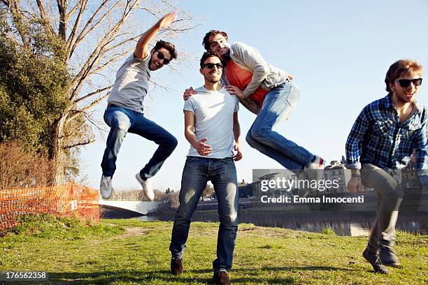 group of friends jumping along the river - guys hanging out foto e immagini stock