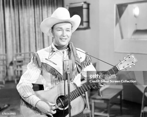 American singer and cowboy actor Roy Rogers playing an acoustic guitar, circa 1940.