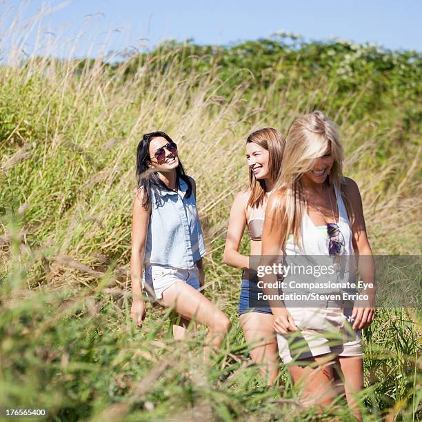 smiling friends walking through meadow - camisa sin mangas fotografías e imágenes de stock