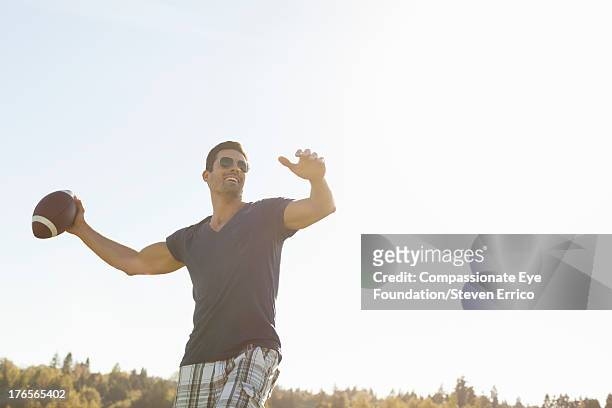 smiling man throwing football outdoors - throwing football stock pictures, royalty-free photos & images