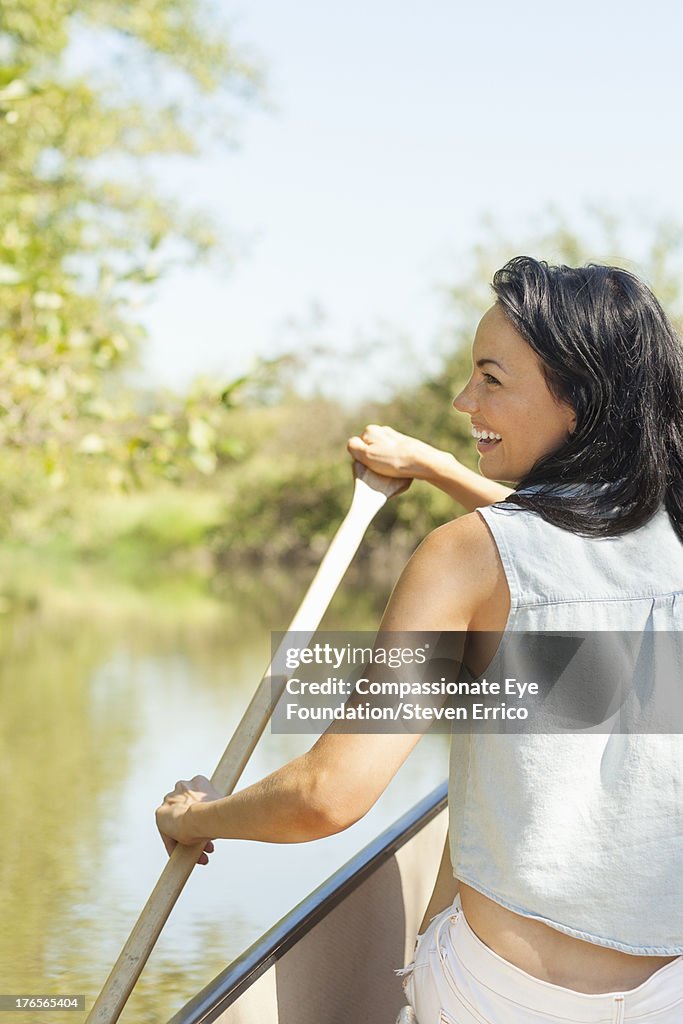 Smiling woman rowing canoe on river
