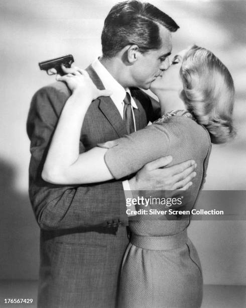 Cary Grant and Eva Marie Saint kissing in a publicity still for 'North By Northwest', directed by Alfred Hitchcock, 1959. Saint is holding a pistol.