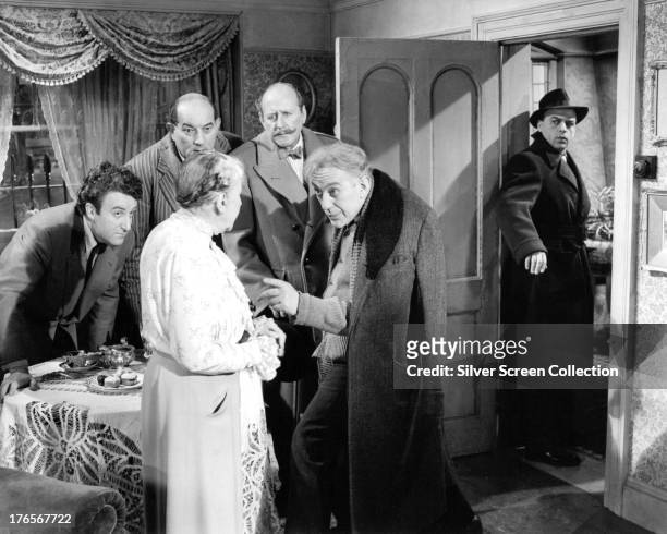 Criminal gang leader Professor Marcus, played by Alec Guinness talks to his landlady, Mrs Wilberforce while the rest of the gang look on in 'The...