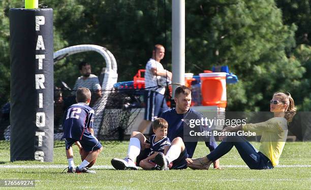 Tom Brady sits with wife Gisele Bundhen and their sons, Benjamin, center, and Jack as the New England Patriots end their last practice on Thursday,...