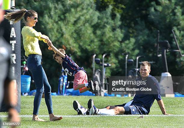 Tom Brady sits while his wife Gisele Bundhen spins their son, Benjamin, as the New England Patriots end their last practice, on Thursday, August 15...