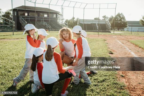 a group of kids in baseball attire converses with their coach - softball sport stock pictures, royalty-free photos & images