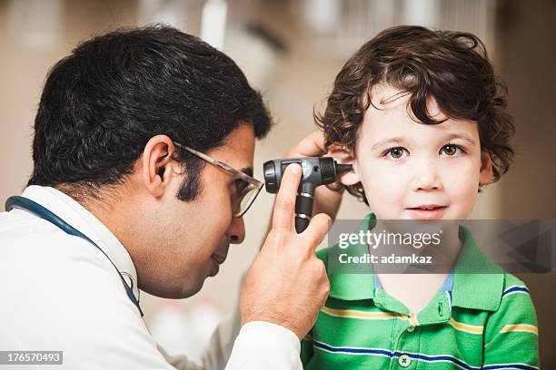 doctor examining little boys ear - otoscope stockfoto's en -beelden