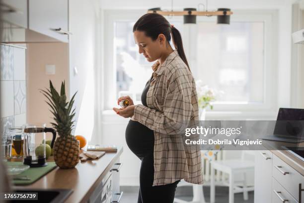 young pregnant woman taking vitamins - prenatal vitamins stock pictures, royalty-free photos & images