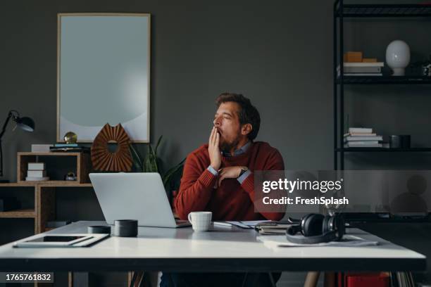 a bored businessman sitting in the office and yawning with his eyes closed - yawn office stockfoto's en -beelden