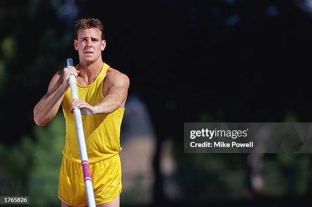 Male pole-vaulter holding pole, close-up