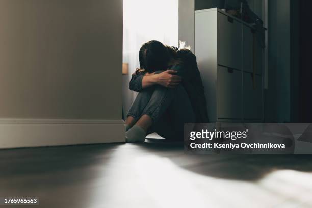 silhouette of sad and depressed woman sitting on the floor at home - fobia fotografías e imágenes de stock