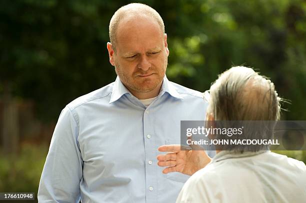 Chairman of Germany's Pirate Party Bernd Schloemer speaks to an unidentified man outside the party's campaign headquarters in Berlin on August 16,...