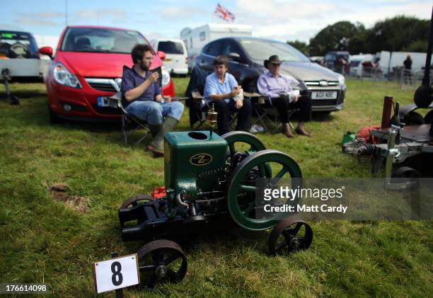 Exhibitors sit besides their stationary engines being shown at the Cornish Steam and Country Fair at the Stithians Showground on August 16, 2013 near...